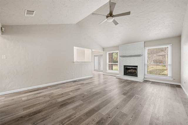 unfurnished living room featuring lofted ceiling, plenty of natural light, a textured ceiling, and wood finished floors