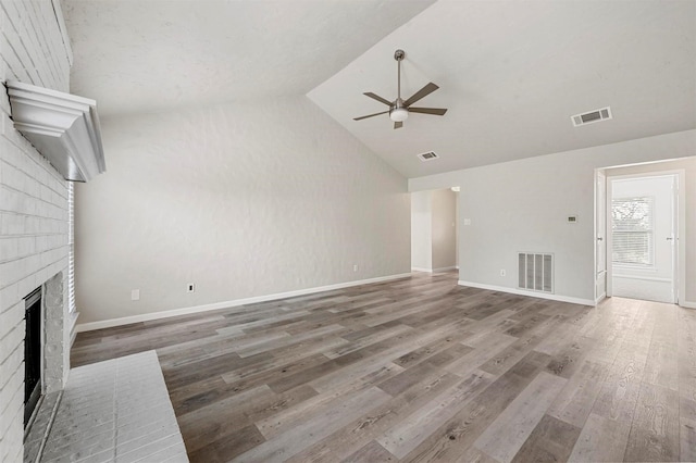 unfurnished living room featuring lofted ceiling, a brick fireplace, visible vents, and wood finished floors