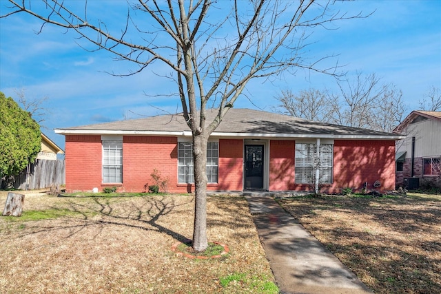 ranch-style home with central AC, brick siding, and fence