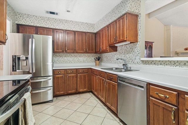 kitchen with light tile patterned floors, stainless steel appliances, a sink, visible vents, and light countertops