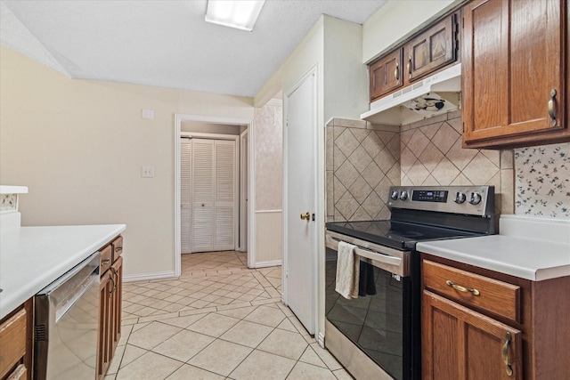 kitchen with light tile patterned floors, under cabinet range hood, stainless steel appliances, light countertops, and decorative backsplash