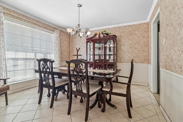 dining space featuring light tile patterned floors, a wainscoted wall, crown molding, an inviting chandelier, and wallpapered walls