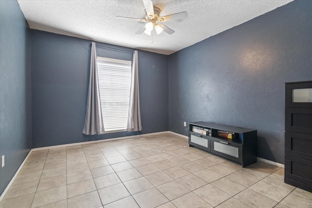 unfurnished room with a textured ceiling, light tile patterned flooring, a ceiling fan, and baseboards