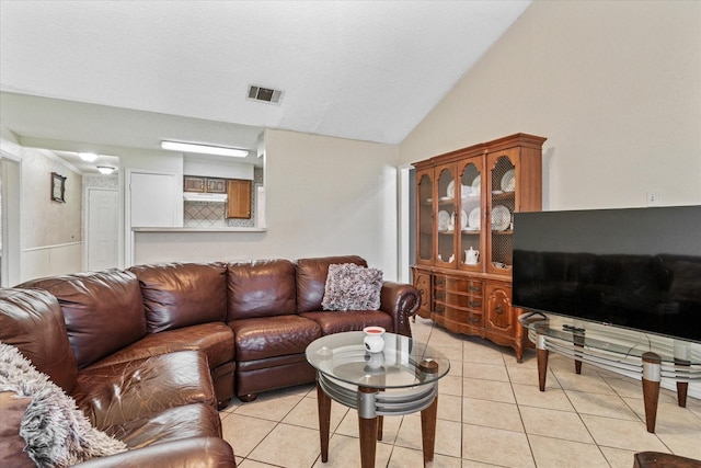 living area with lofted ceiling, light tile patterned flooring, and visible vents