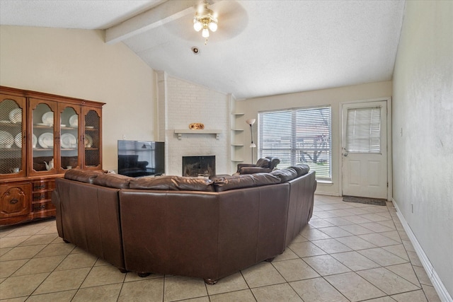 living area featuring vaulted ceiling with beams, a textured ceiling, light tile patterned flooring, a ceiling fan, and a brick fireplace