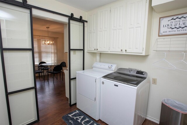 laundry room with dark wood finished floors, washer and clothes dryer, cabinet space, a barn door, and a chandelier