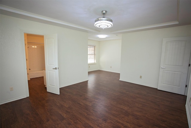 empty room with crown molding, dark wood-style flooring, and baseboards