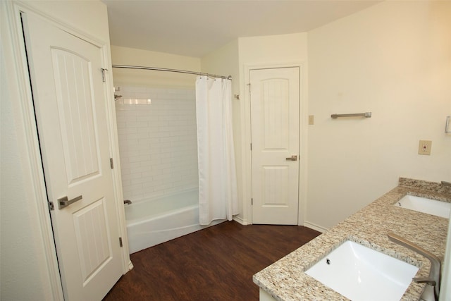 full bath featuring double vanity, a sink, and wood finished floors