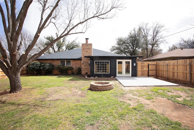 rear view of house featuring a patio, a fenced backyard, a fire pit, a yard, and a chimney