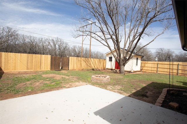 view of yard featuring a fire pit, a patio area, an outdoor structure, and a fenced backyard