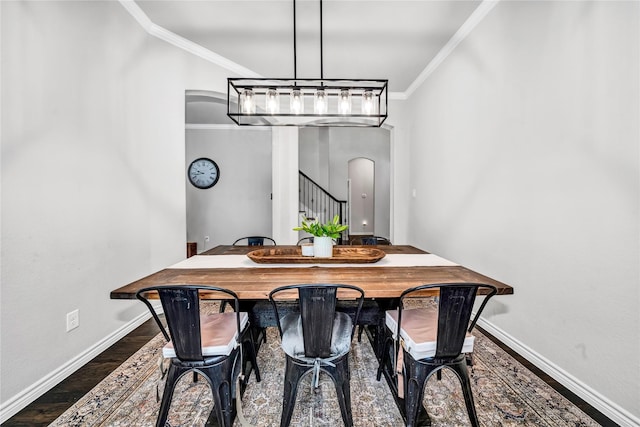 dining room with arched walkways, baseboards, wood finished floors, and crown molding