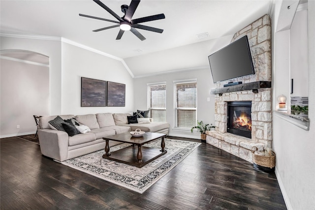 living room featuring ceiling fan, ornamental molding, dark wood-style flooring, and a fireplace