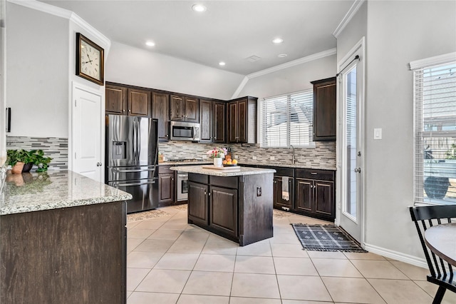 kitchen featuring light tile patterned floors, ornamental molding, stainless steel appliances, and dark brown cabinets