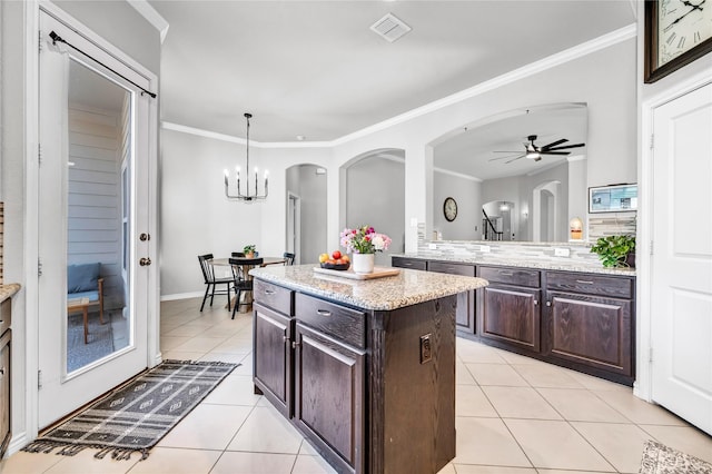 kitchen with crown molding, visible vents, light tile patterned flooring, dark brown cabinets, and ceiling fan with notable chandelier