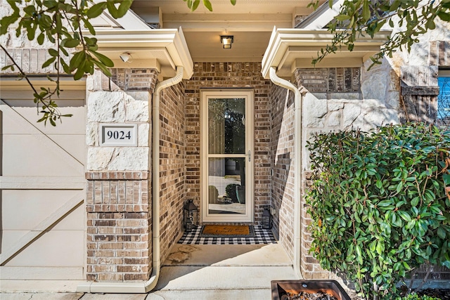 entrance to property with a garage and brick siding