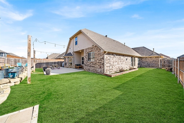 rear view of house with a yard, a patio, brick siding, and a fenced backyard