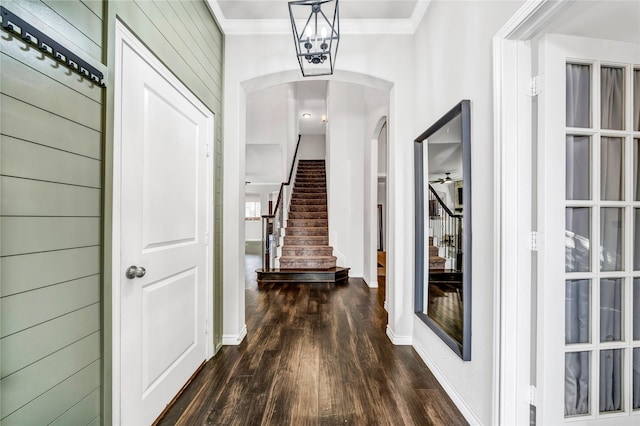 hallway with baseboards, arched walkways, ornamental molding, dark wood-style flooring, and stairs