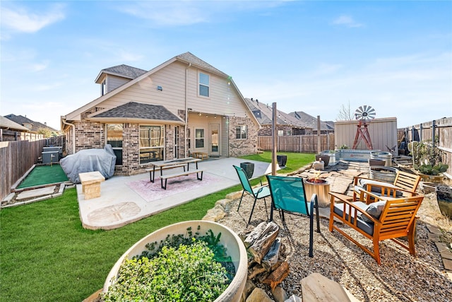 rear view of house with an outbuilding, a fenced backyard, a fire pit, a storage shed, and a yard