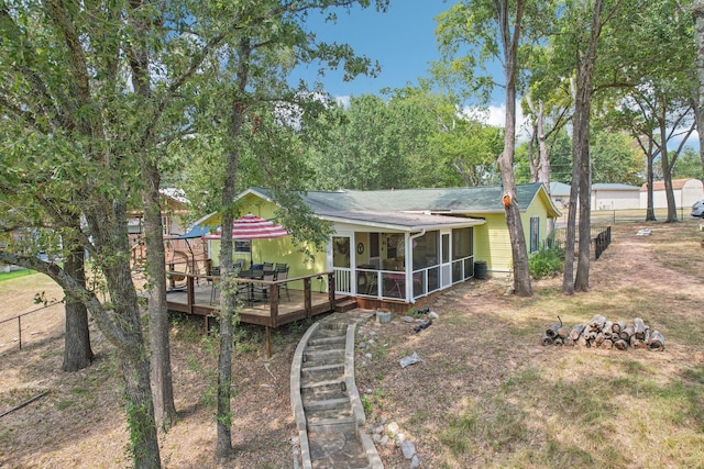 back of property featuring a deck, fence, and a sunroom