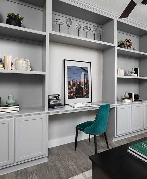 interior space featuring light wood finished floors, built in desk, a ceiling fan, and baseboards