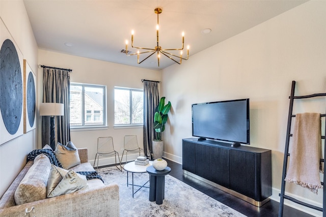 living room featuring baseboards, wood finished floors, and an inviting chandelier