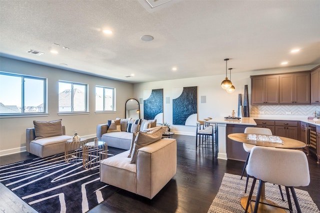 living area featuring baseboards, visible vents, dark wood-style flooring, and recessed lighting