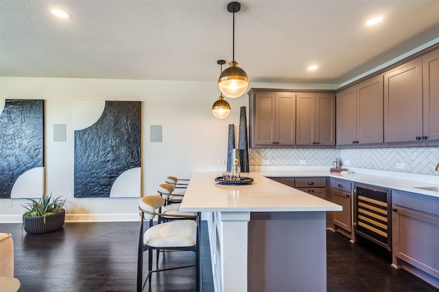 kitchen with beverage cooler, a breakfast bar, a peninsula, light countertops, and backsplash