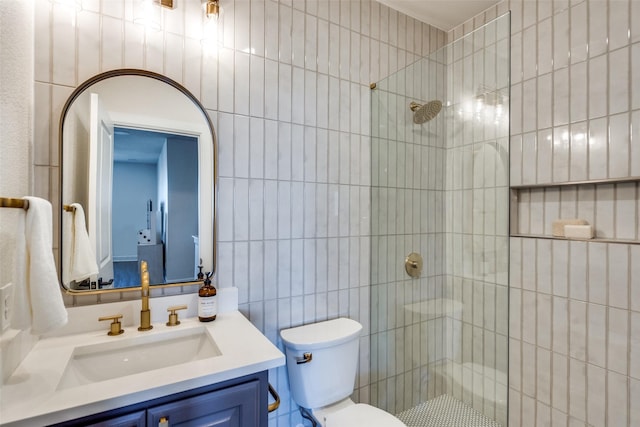 bathroom with toilet, a tile shower, tile walls, and vanity