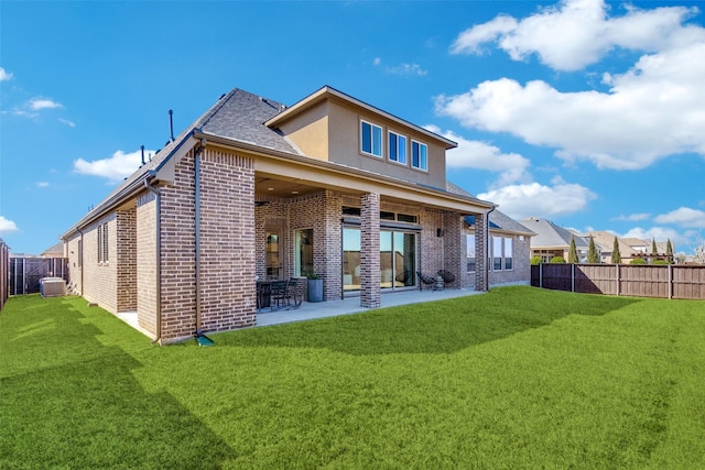 rear view of property with a yard, a patio, brick siding, and a fenced backyard