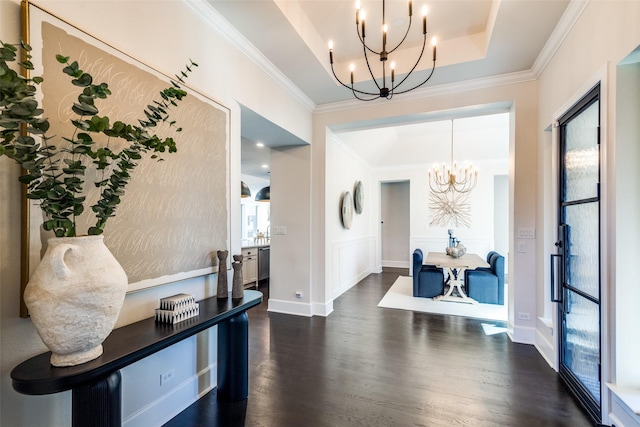 foyer entrance featuring dark wood-style floors, a chandelier, a tray ceiling, and ornamental molding