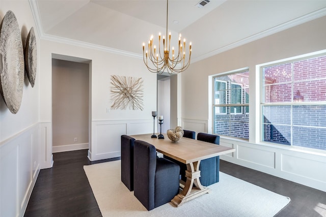 dining space with dark wood finished floors, visible vents, a decorative wall, ornamental molding, and a chandelier