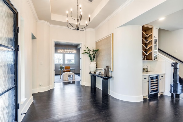 hallway featuring a chandelier, beverage cooler, a raised ceiling, and dark wood finished floors