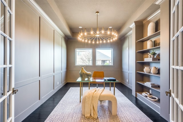 office area featuring dark wood-style floors, a tray ceiling, a decorative wall, and an inviting chandelier