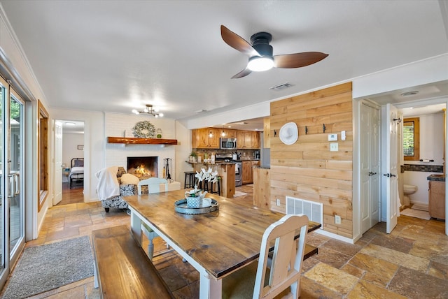 dining space featuring crown molding, stone tile flooring, visible vents, and a fireplace