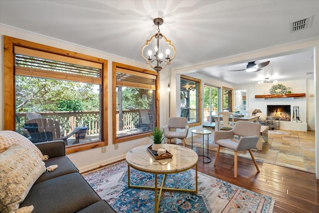 living room with a fireplace, visible vents, baseboards, ornamental molding, and hardwood / wood-style floors