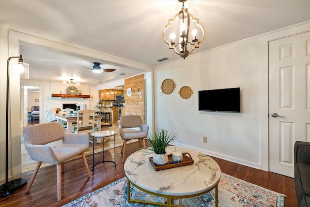 living area with visible vents, wood finished floors, and ceiling fan with notable chandelier