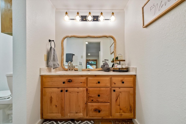 bathroom with toilet, a textured wall, ornamental molding, and vanity