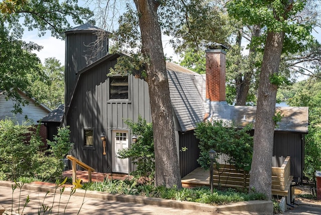 exterior space featuring board and batten siding, a chimney, and a deck