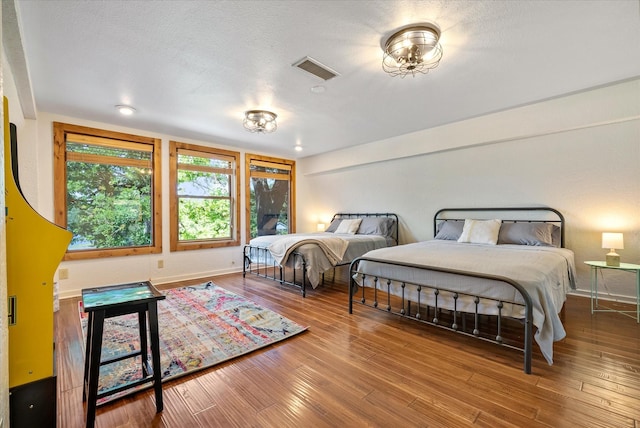 bedroom featuring baseboards, visible vents, and wood finished floors