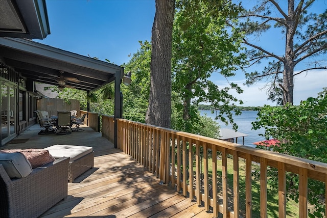 wooden deck with ceiling fan, outdoor dining area, and a water view