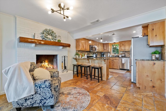 interior space featuring crown molding, stone tile flooring, visible vents, and a brick fireplace