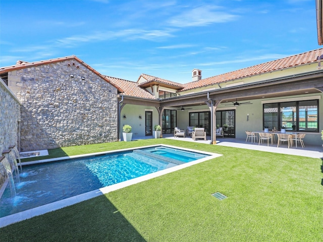 rear view of property featuring stucco siding, a lawn, a tile roof, an outdoor living space, and ceiling fan