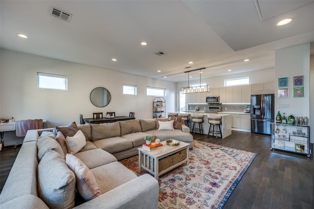 living room with dark wood-type flooring, a wealth of natural light, and visible vents