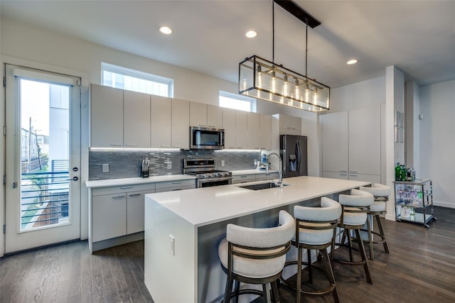 kitchen featuring tasteful backsplash, appliances with stainless steel finishes, dark wood-style flooring, and a sink