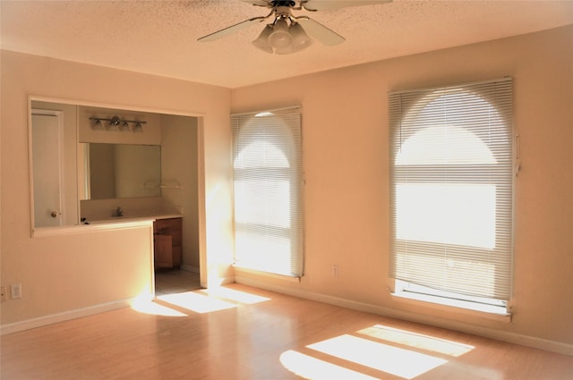 interior space featuring ceiling fan, a textured ceiling, baseboards, and wood finished floors