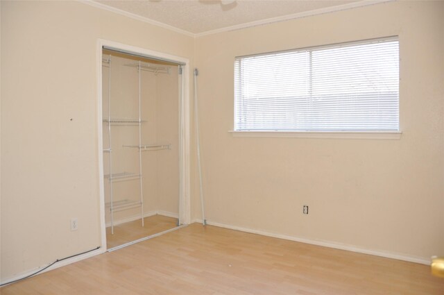 unfurnished bedroom with crown molding, baseboards, a closet, and wood finished floors