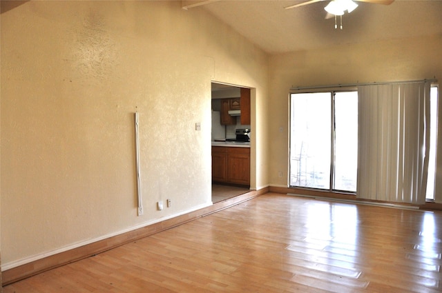 spare room with light wood finished floors, ceiling fan, baseboards, and vaulted ceiling