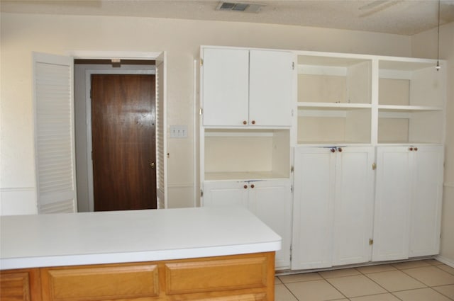 kitchen with light tile patterned floors, open shelves, light countertops, and visible vents