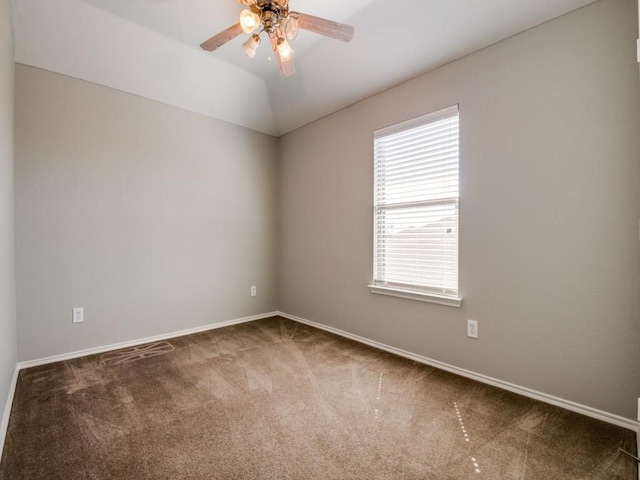 empty room with vaulted ceiling, carpet flooring, baseboards, and ceiling fan