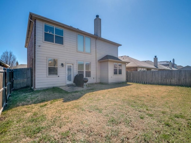 rear view of property featuring a yard, a fenced backyard, and a chimney